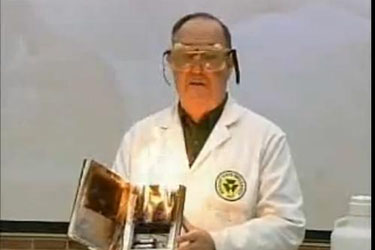 Man in lab coat showing a book with burning pages