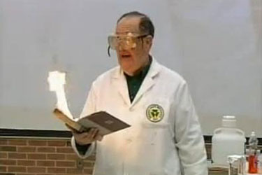 Man in lab coat reading from a book that appears to be on fire